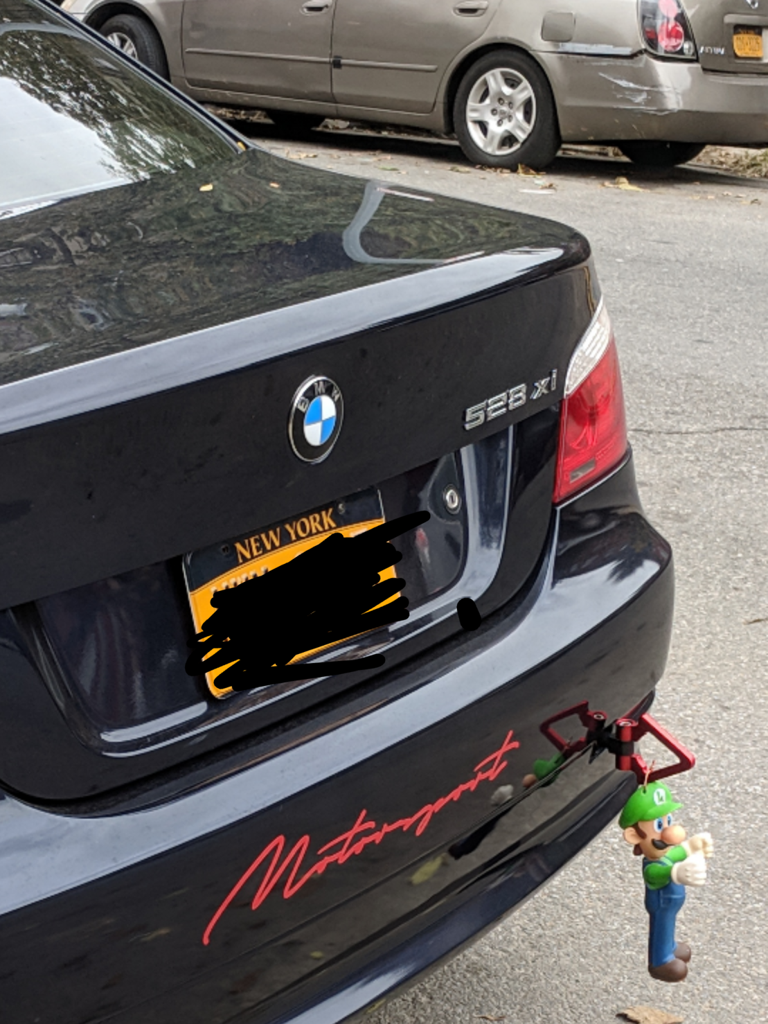 a toy Luigi attached to a hook on the rear bumper of the car