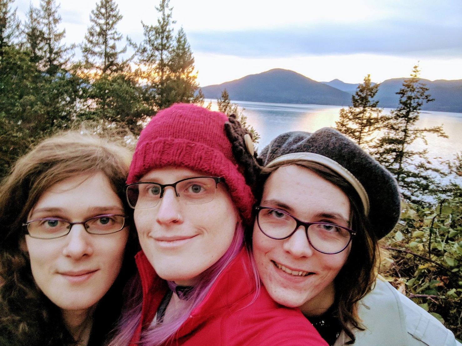three smiling women in front of a sweeping mountainscape