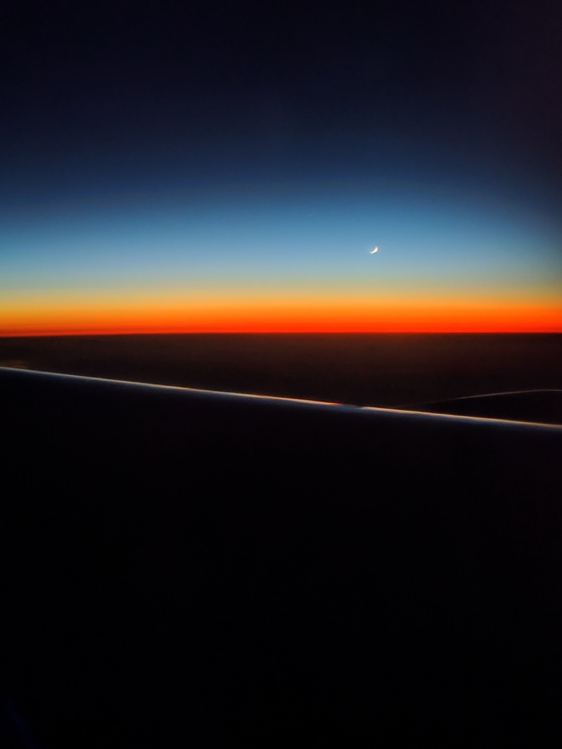 a blue, orange, and red gradient sky, with a small crescent moon
