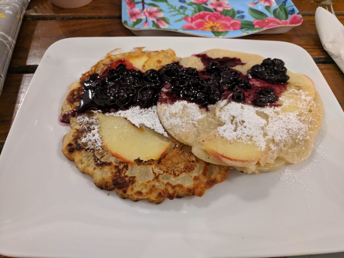 apple crepes covered in powdered sugar and blueberry compote