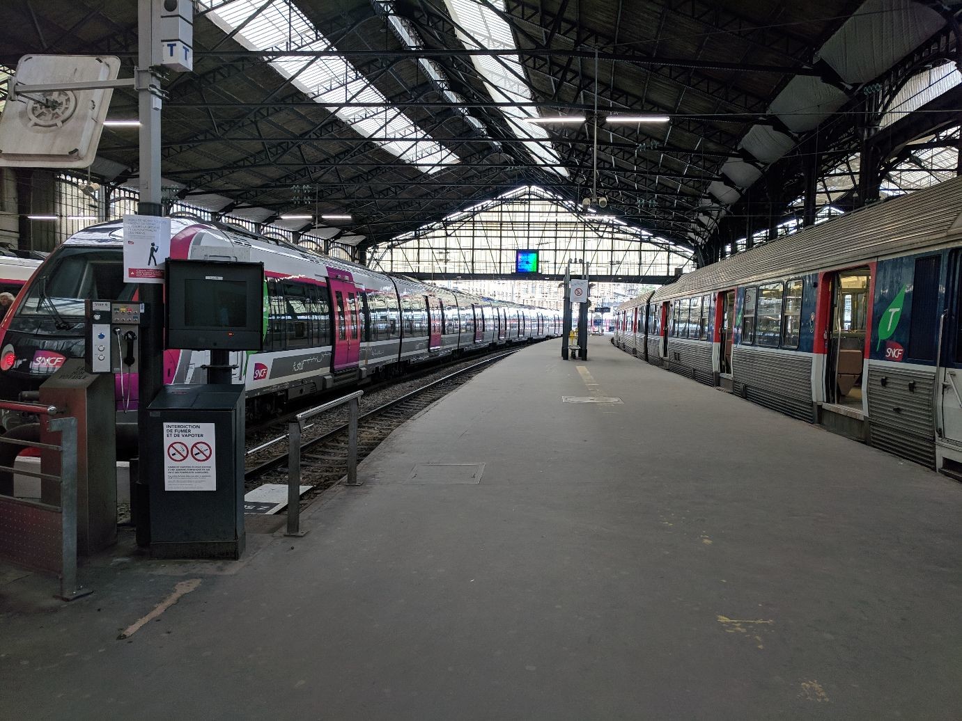 a long train platform with two trains waiting for passengers