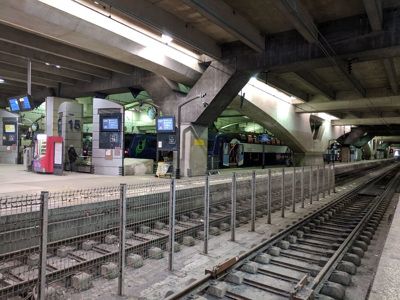 a train under a concrete ceiling as seen from across two tracks