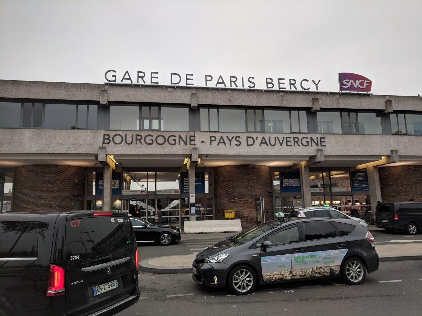 a sad, 70s looking building, grey concrete and shabby brick. large letters spell Gare de Paris Bercy