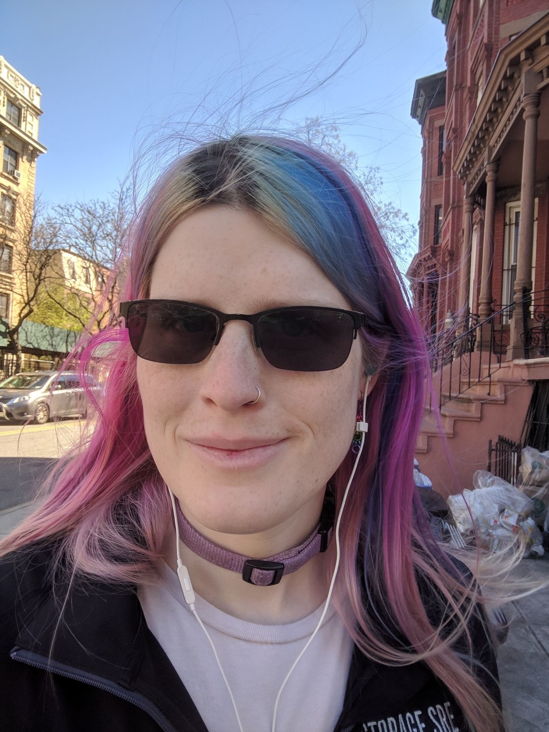 a girl taking a selfie on a street. her glasses are completely opaque glass
