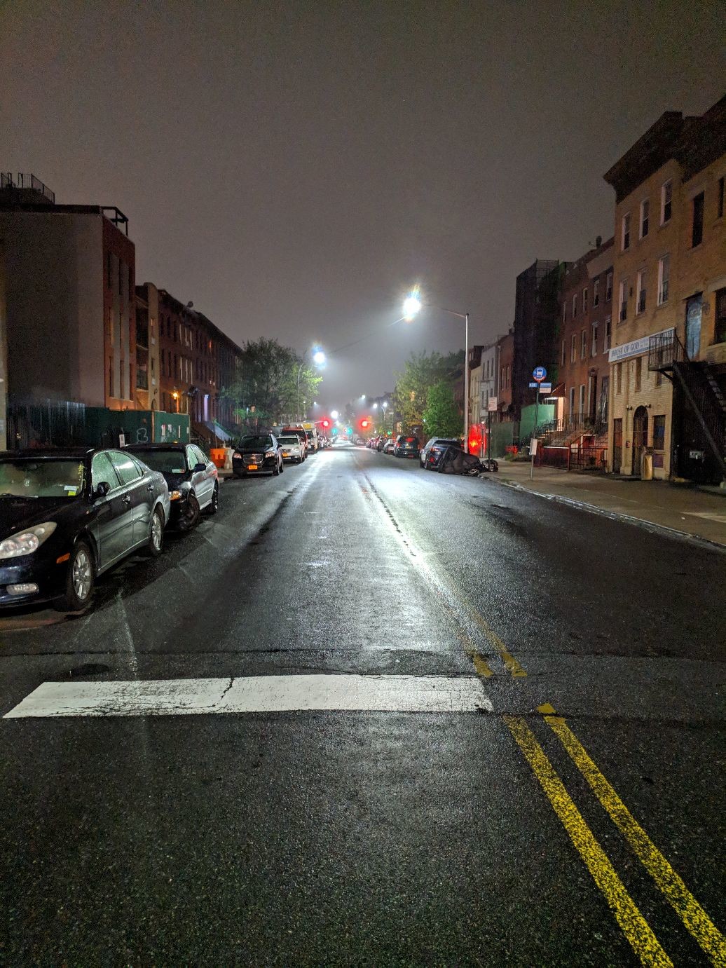 a very misty, foggy street lit by street lights and distant stoplights