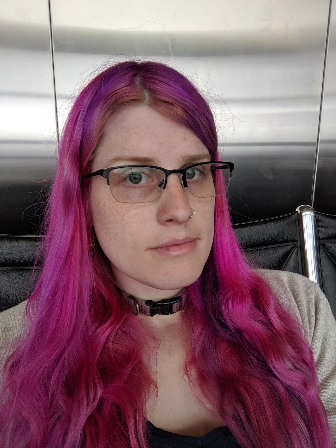 me sitting in an airport, floofy pink hair cascading down my shoulders 