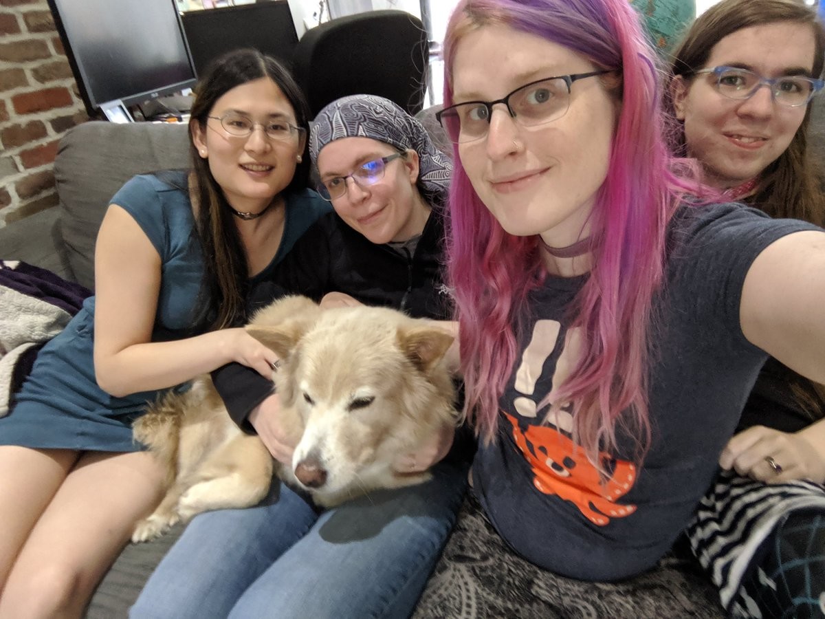 Four smiling women and a reluctant dog on a couch