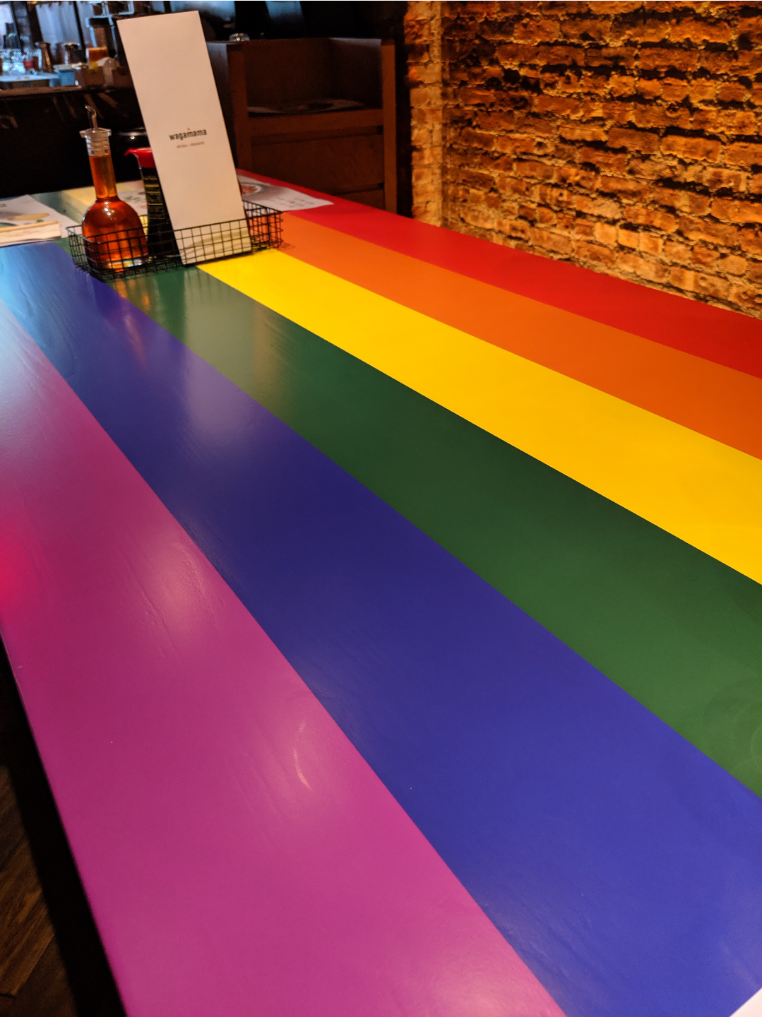 a table in a restaurant painted with the six colour rainbow flag