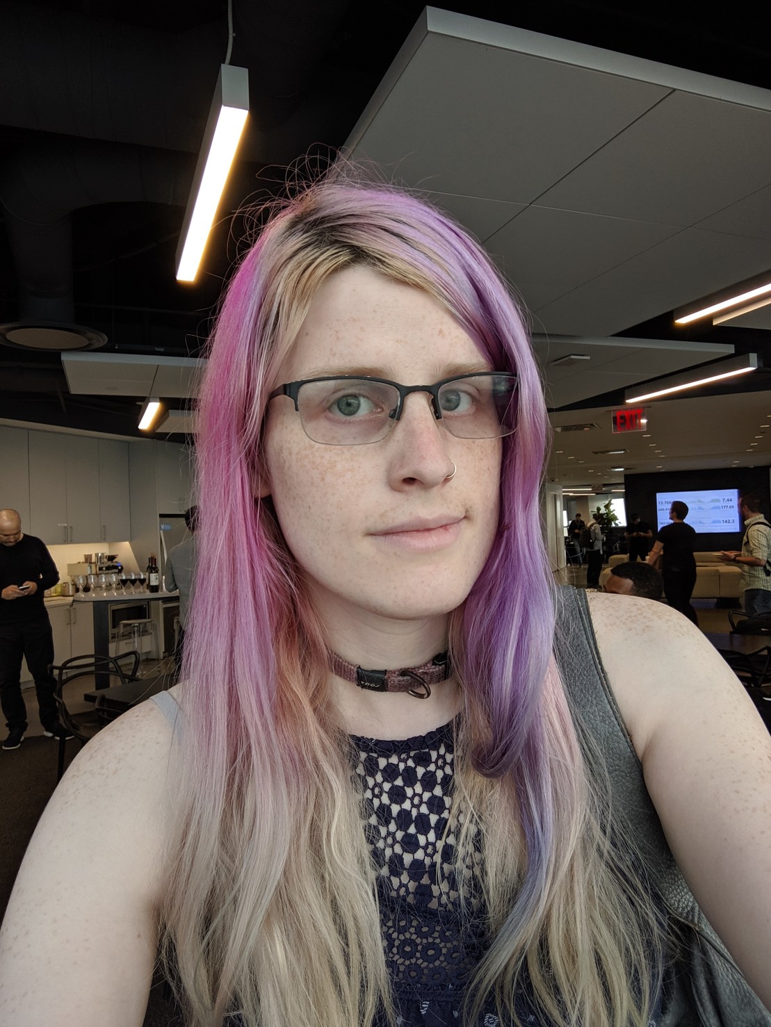 a slightly smiling woman with pink hair and glasses