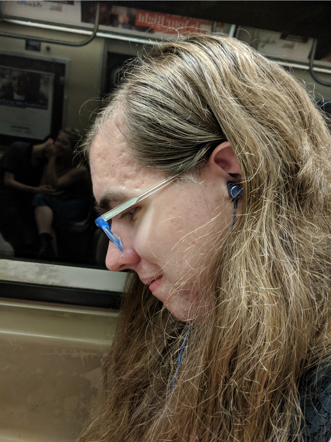 a smiling Natalie on a subway wearing headphones