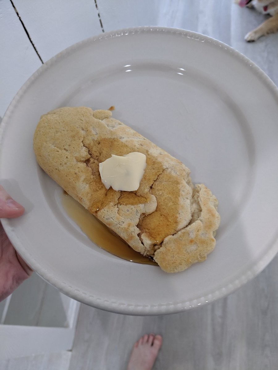 A pancake folded into a tube, covered in butter and syrup