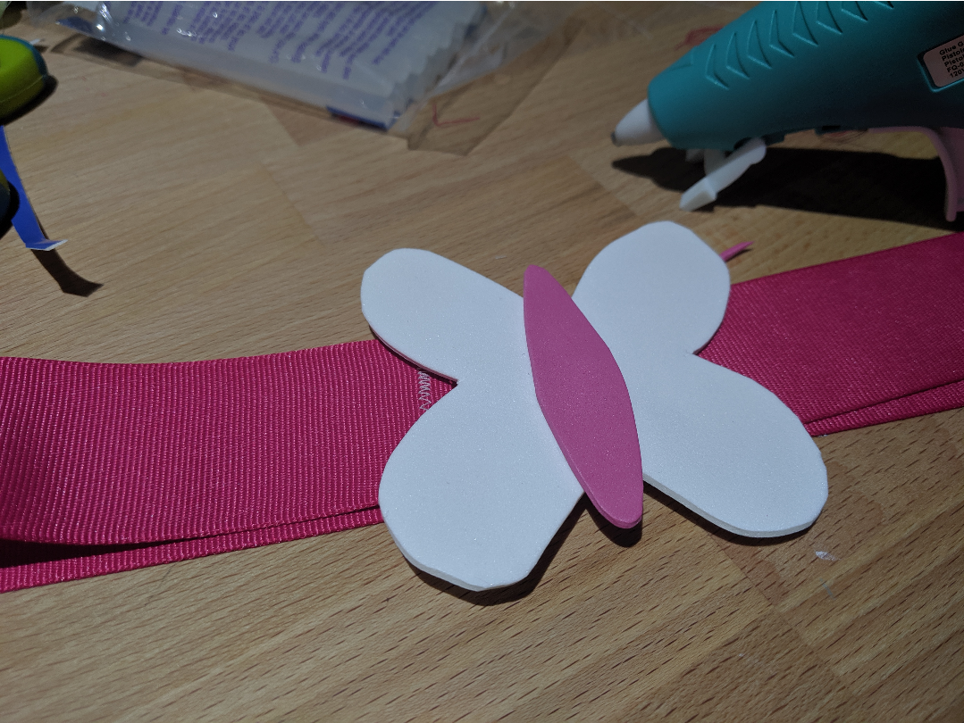 a pink ribbon belt with a white butterfly clasp