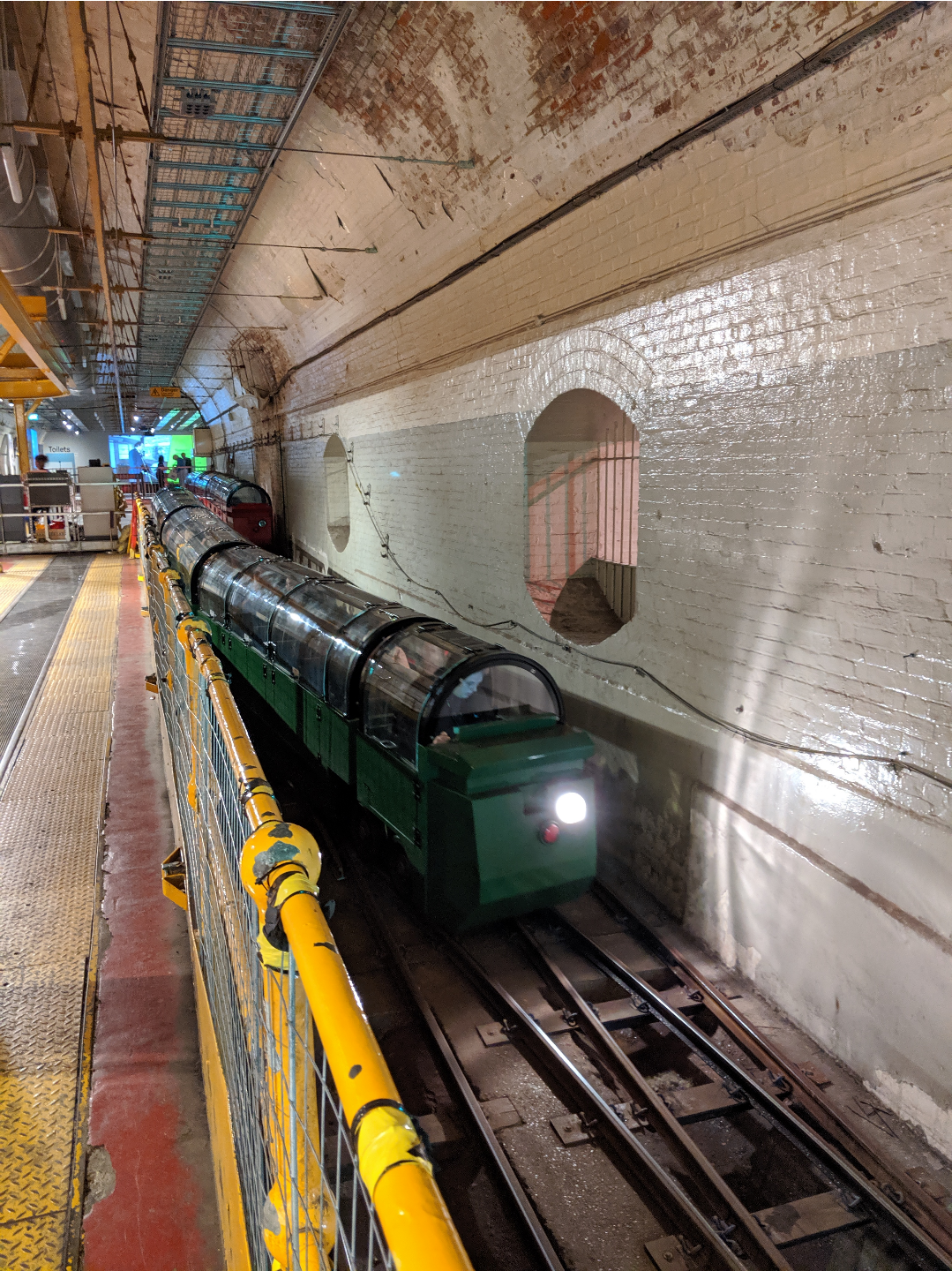 a squat green narrow gauge train heading down a slope