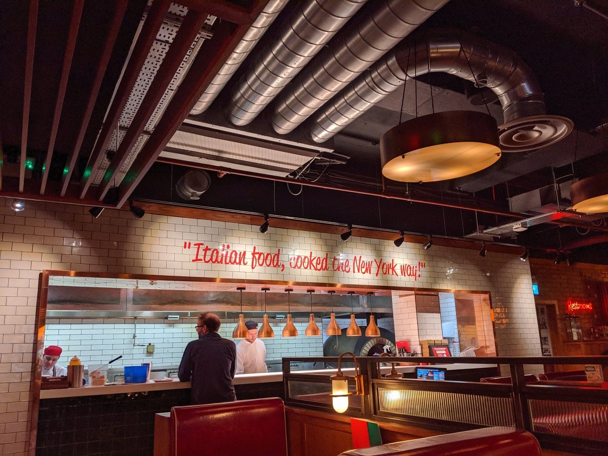 A sign on a wall of a restaurant reading Italian food, cooked the New York Way