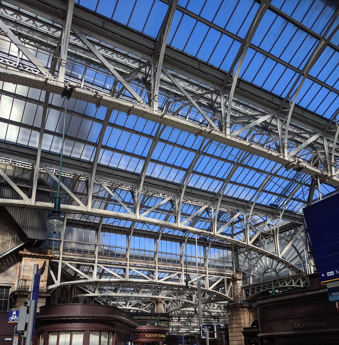A glass and iron vaulted roof over a train station