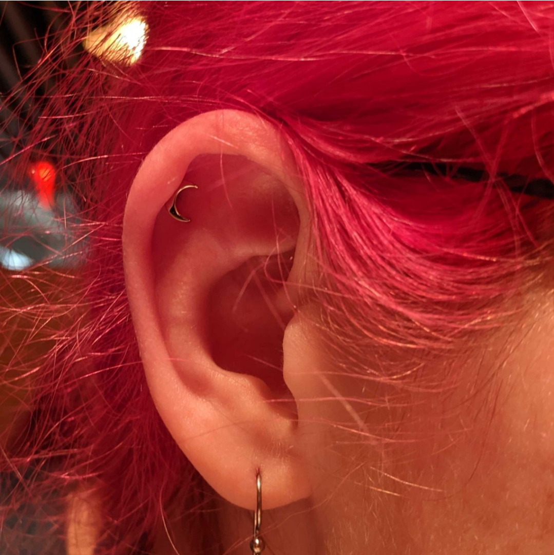 a small silver moon in the helix of my ear