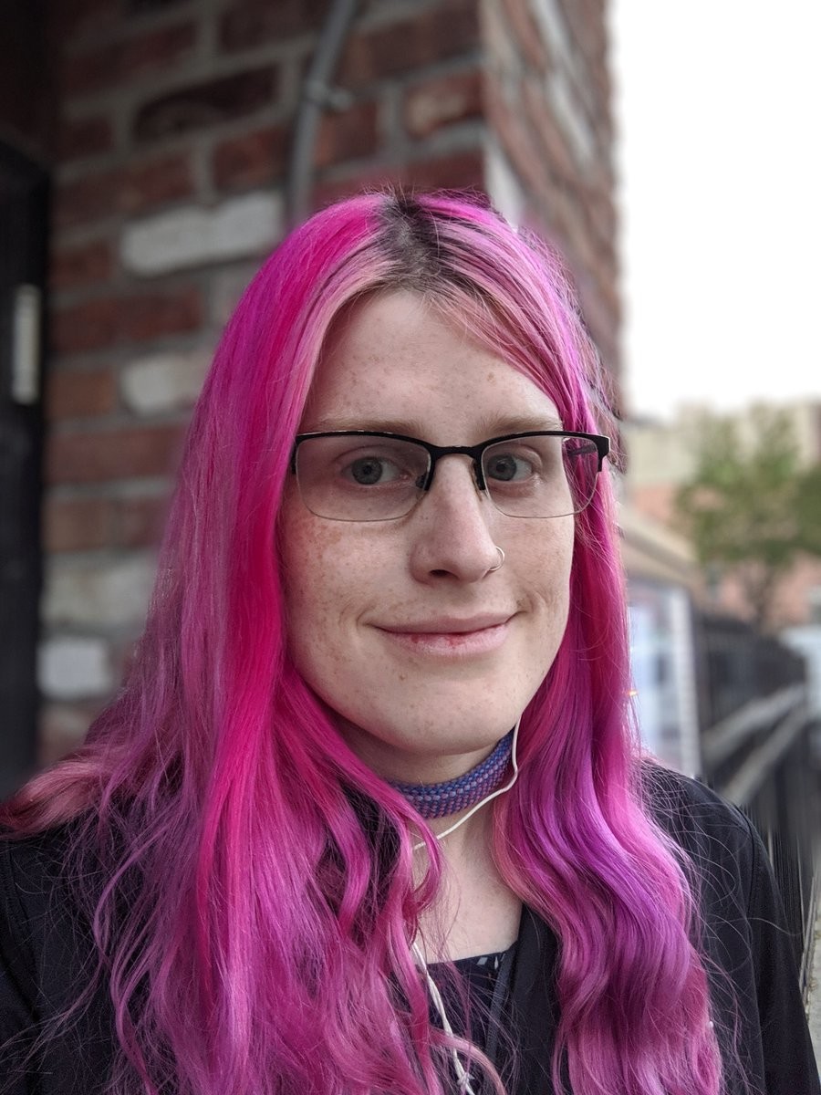 A smiling woman with long pink hair