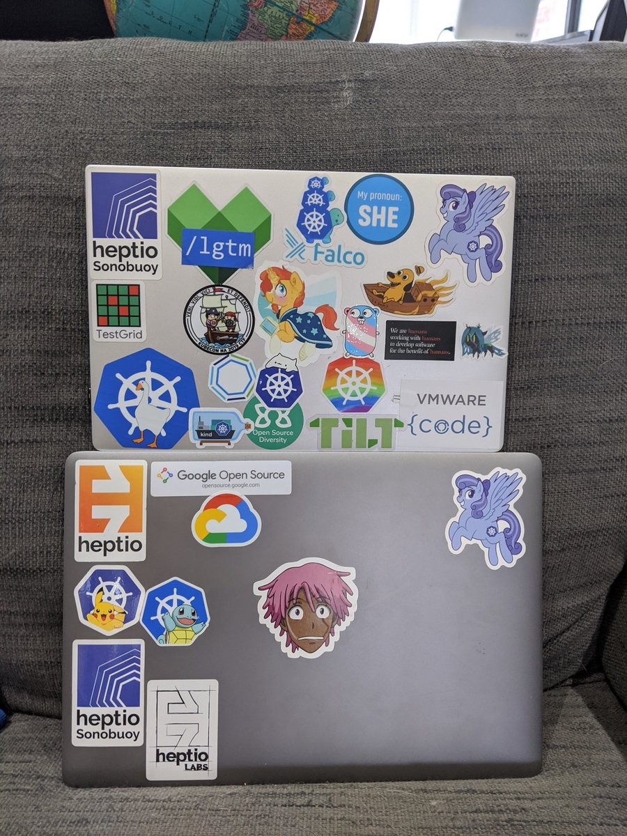 A bunch of colourful Kubernetes and software project related stickers. Highlights include a trans pride gopher, cartoon kubernetes pony, rainbow k8s logo, and the face of Kaz Kan from Neo Yokio