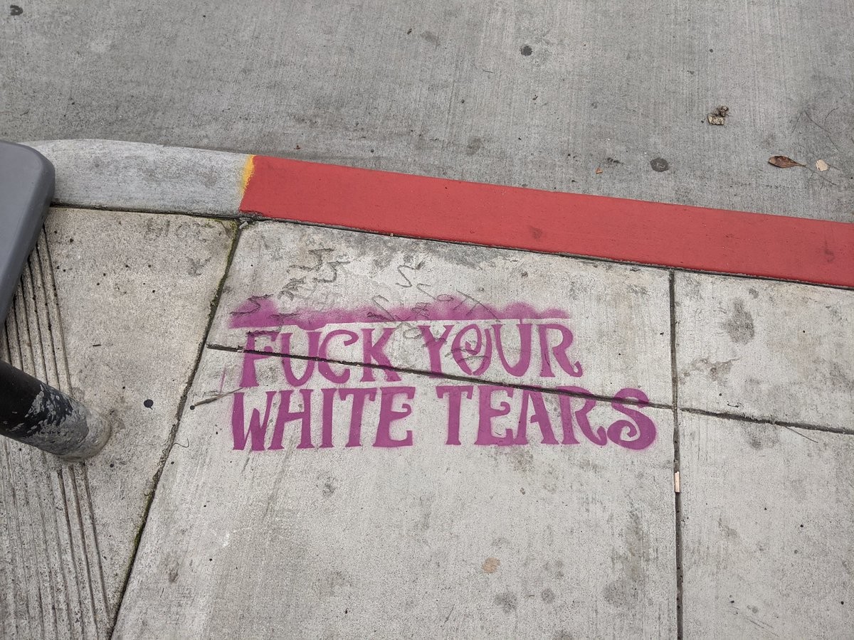 FUCK YOUR WHITE TEARS spray painted on a dirty sidewalk
