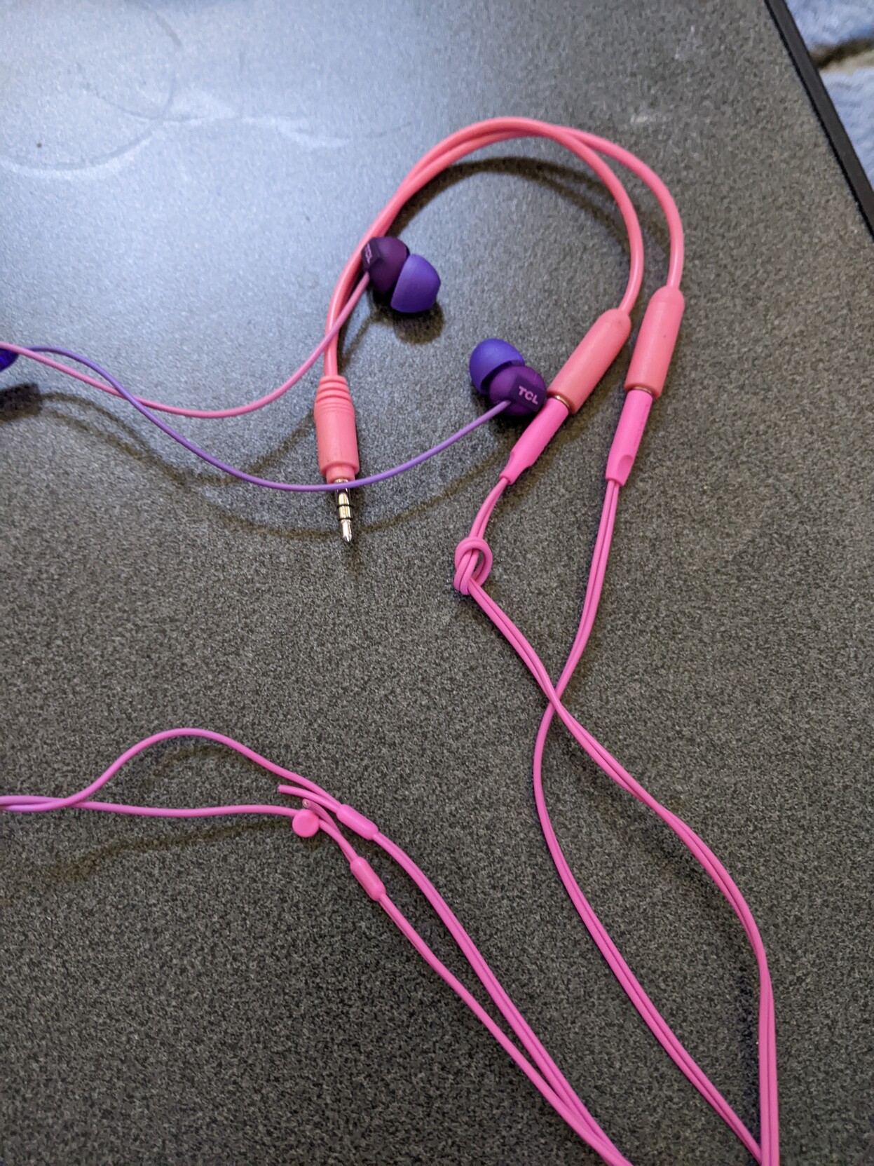 Two pairs of earbuds, plugged into a splitter, each with one cable severed