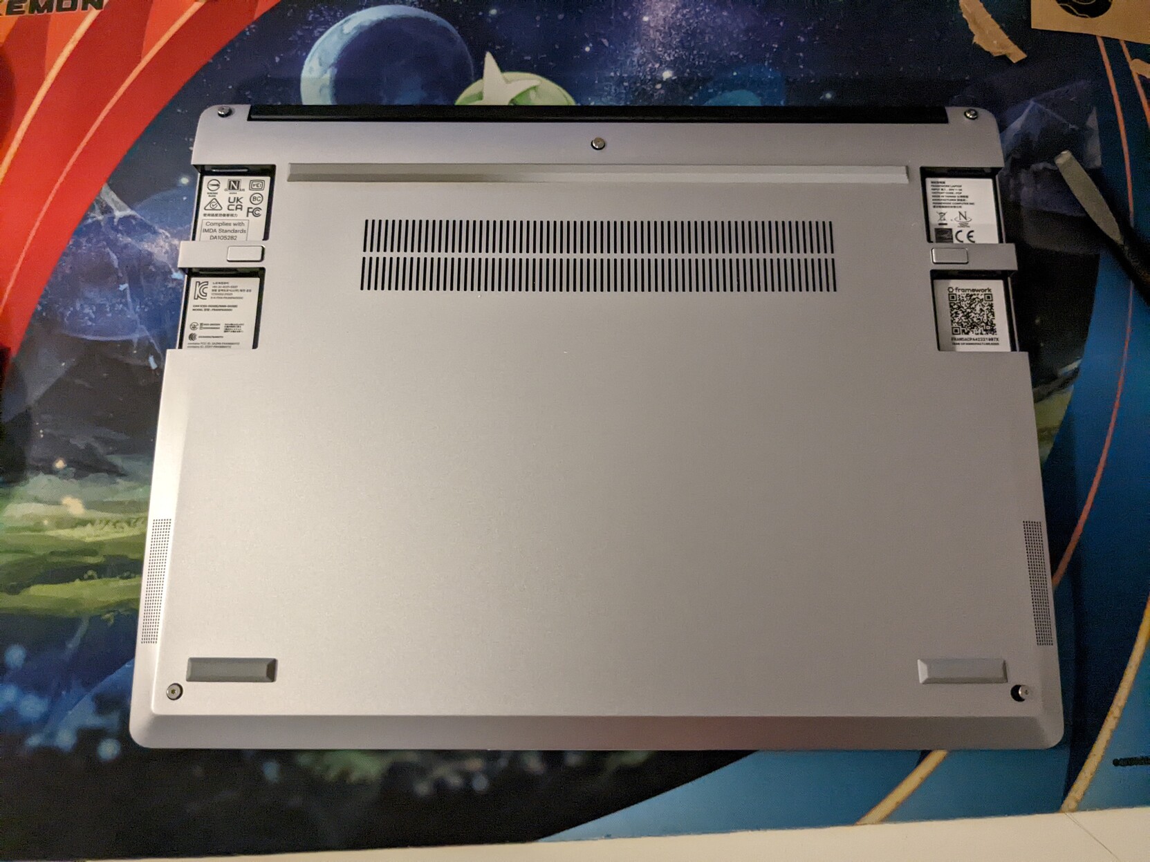 A laptop upside down, screws unscrewed